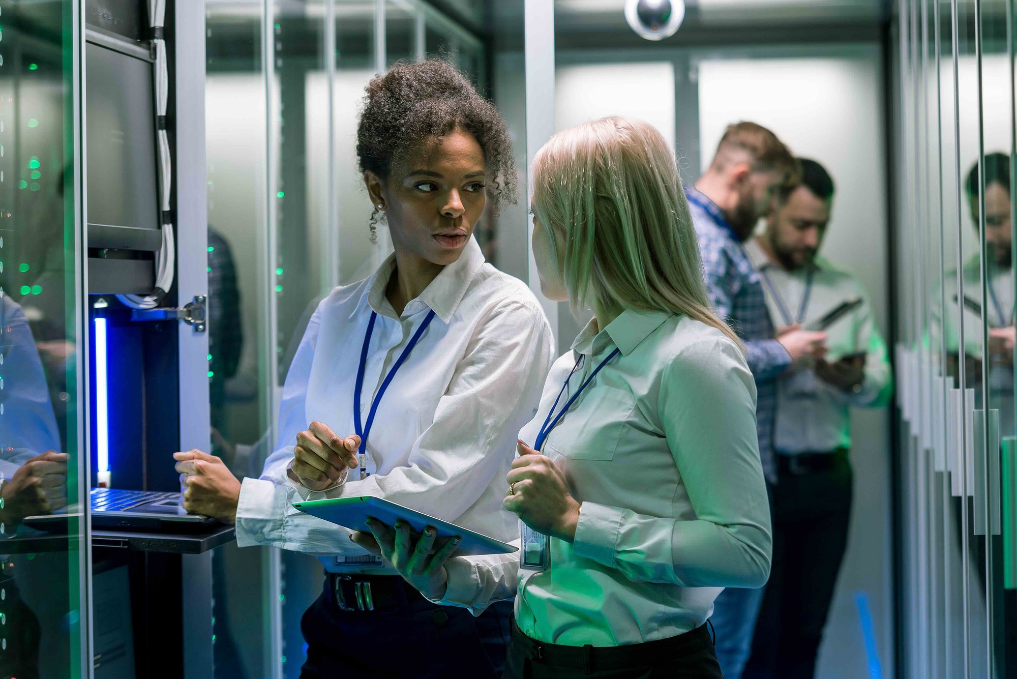 IT professionals discussing firewall professional services in a data center environment with servers and networking equipment.