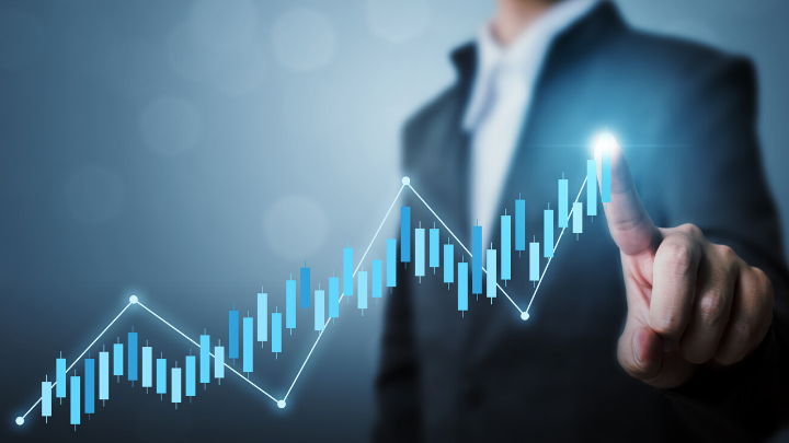 a man in a suit in the background out of focus pointing to the chart overlay