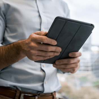 a photo of a male employee using a tablet while holding it with both hands