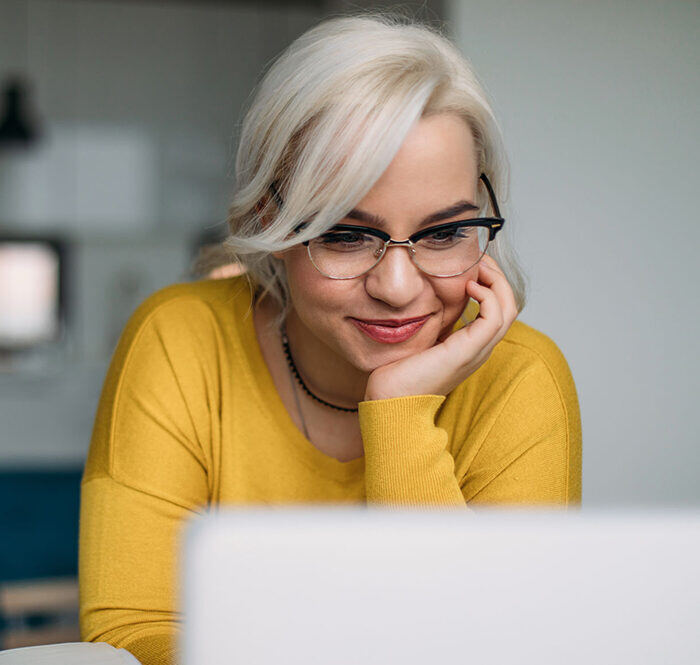 Close up of a young blond woman using her laptop at home