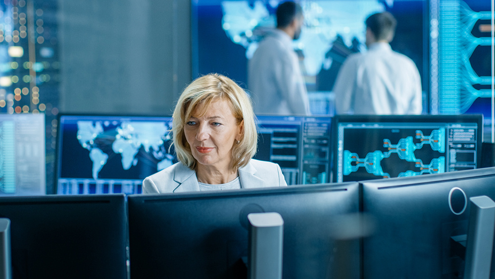 System Monitoring Room Professional Female Operator Observes Correct Functioning of the Facility. In the Background People Working with Interactive Map.