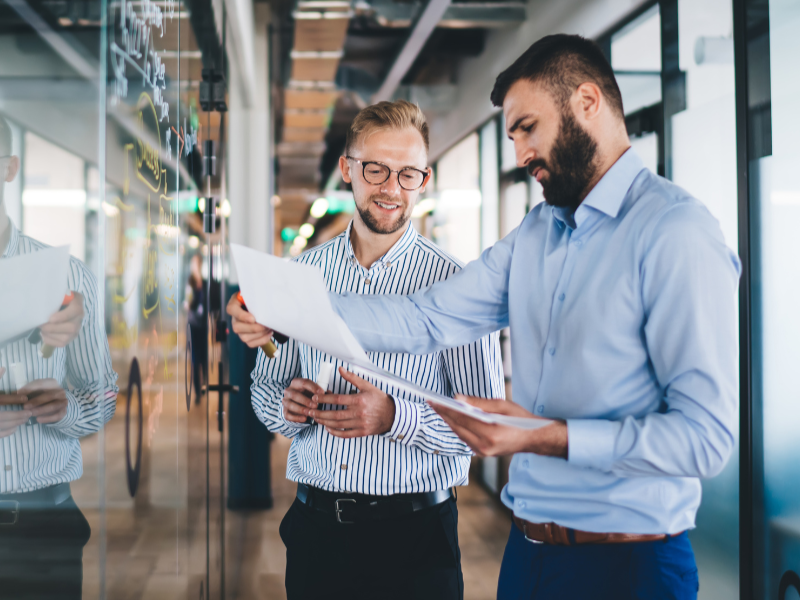 Two men at an office reviewing information in a printed report