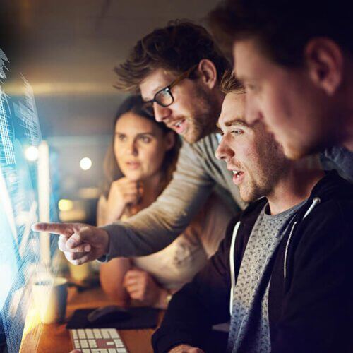 Shot of a group of programmers working on a computer code at night